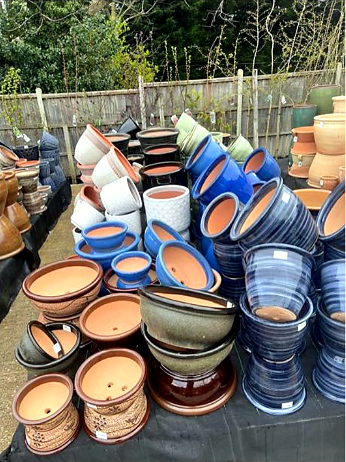 Stacks of blue and dark glazed garden pots in the outdoor pot yard