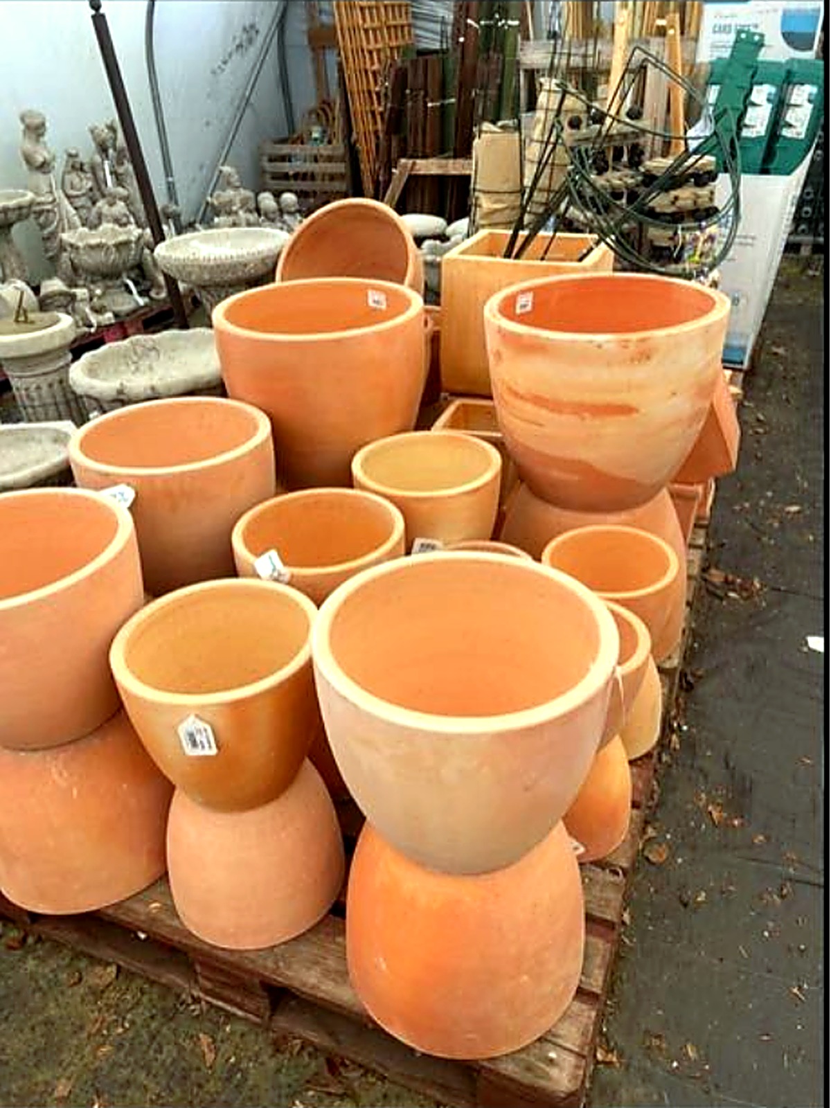 Stacks of terracotta and stone pots with garden ornaments behind