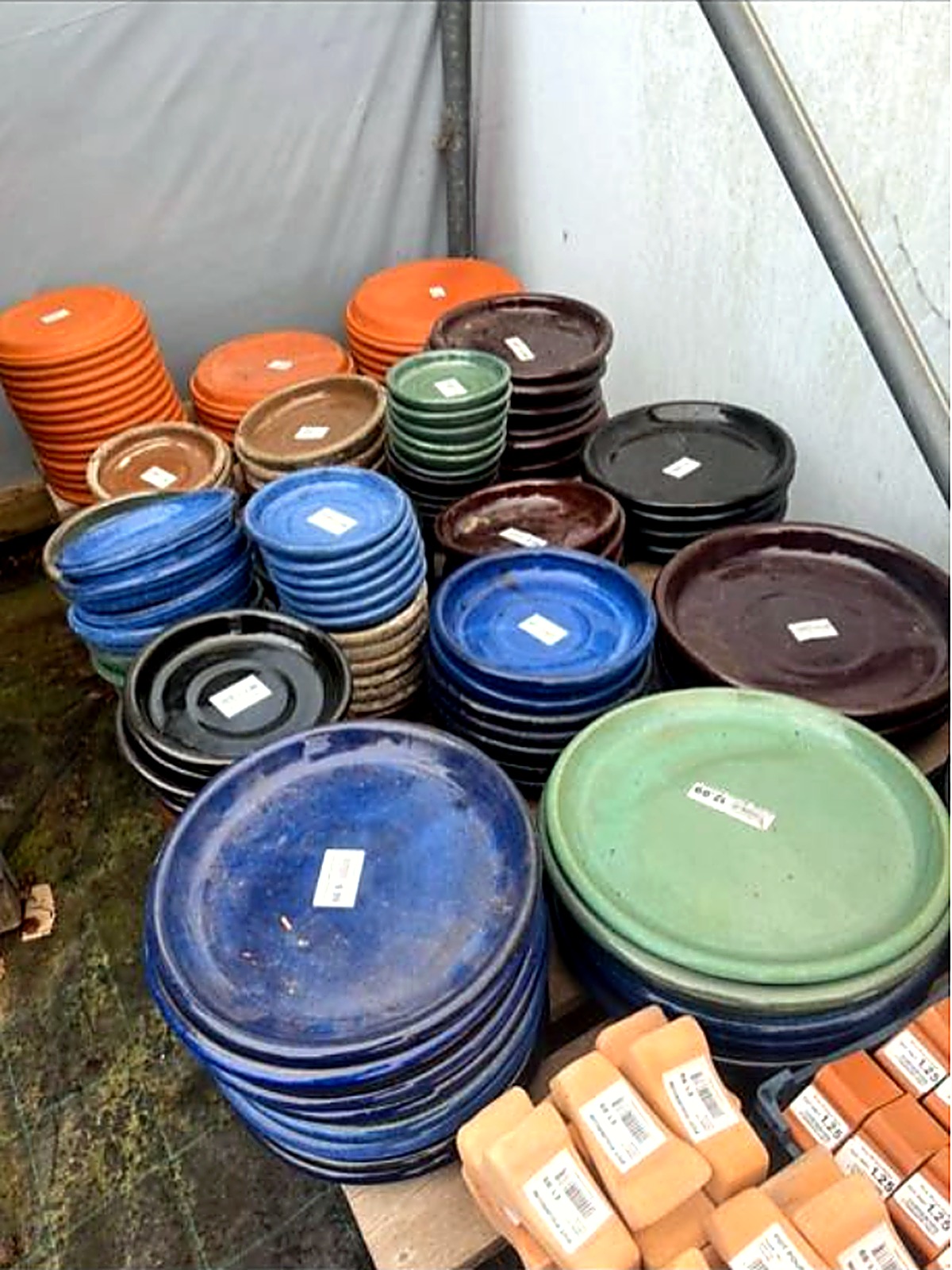 Colourful glazed plant saucers in blue, green and terracotta