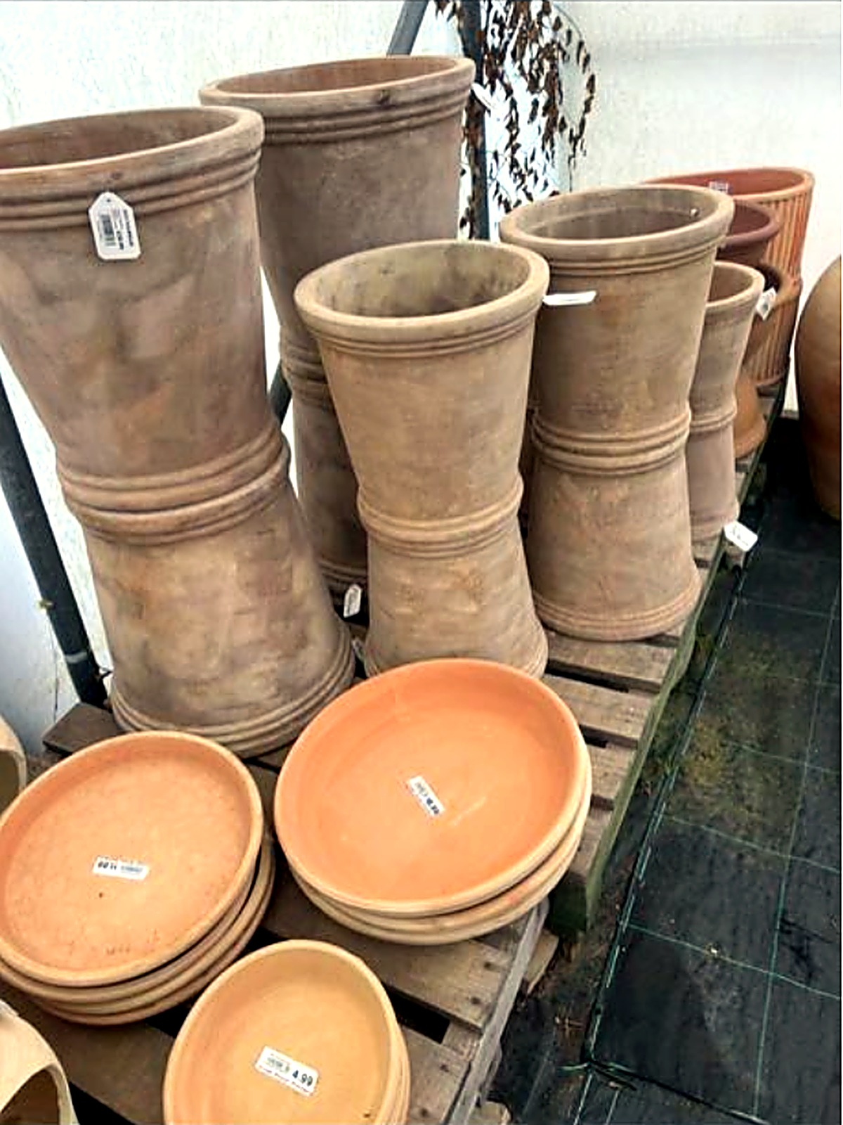 Large weathered stone-colour planters stacked on wooden pallets