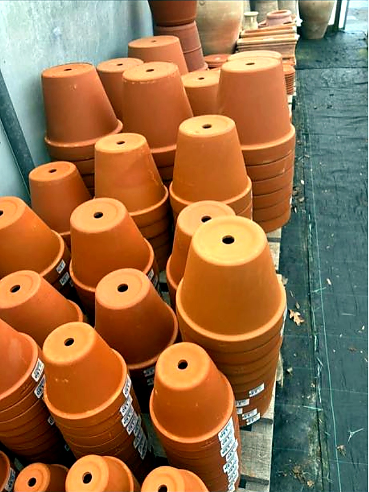 Large terracotta pots stacked on a wooden pallet
