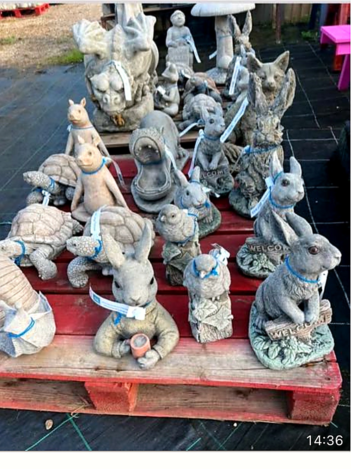 Stone rabbits, tortoises and owls on a pallet of garden animal ornaments