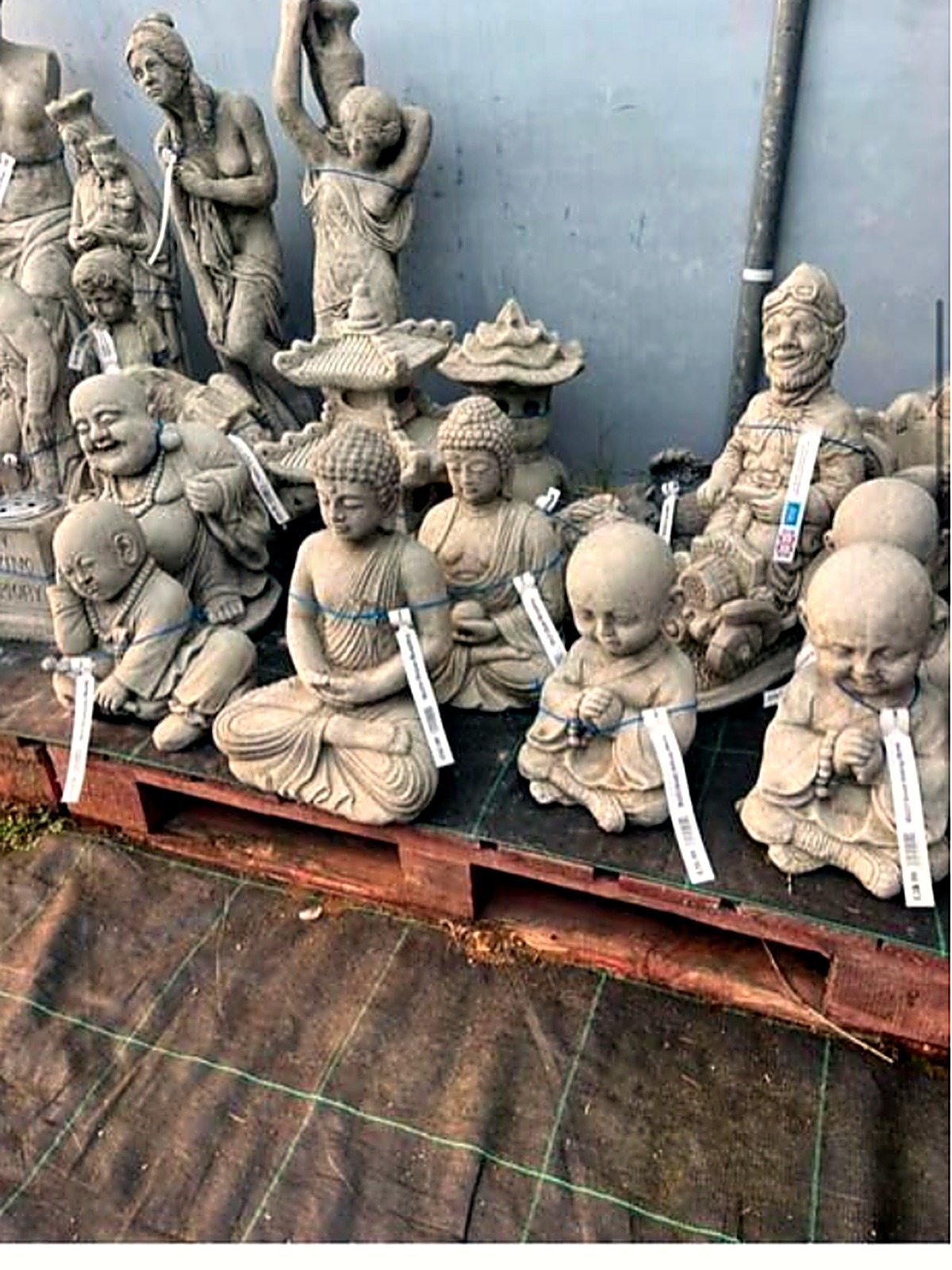 Stone Buddha and classical figure ornaments lined up on a pallet