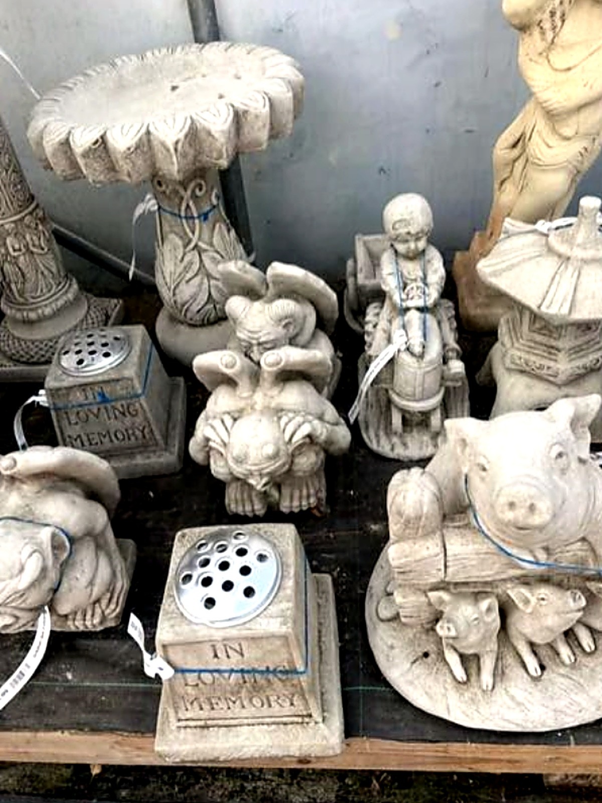 Stone bird bath, gargoyle and pig family ornaments on display